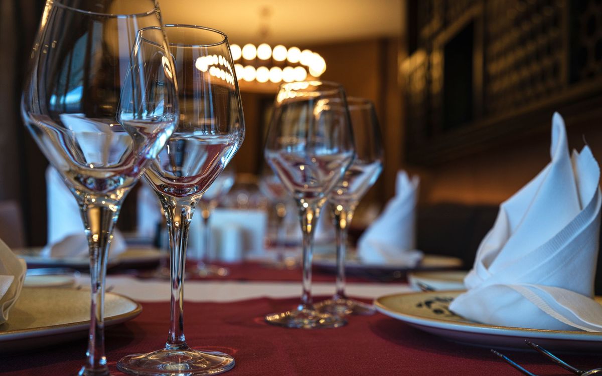 Close-up of a dinner table set with wine glasses and folded napkins in a warmly lit dining room.