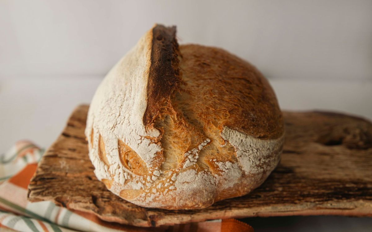 Golden baked loaf of bread resting on a rustic wooden board.