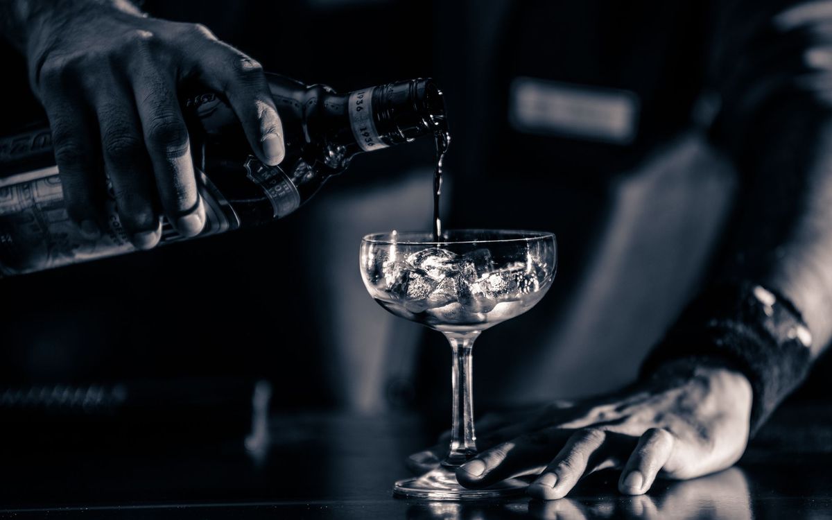 Bartender pouring liquor into a chilled cocktail glass with ice.