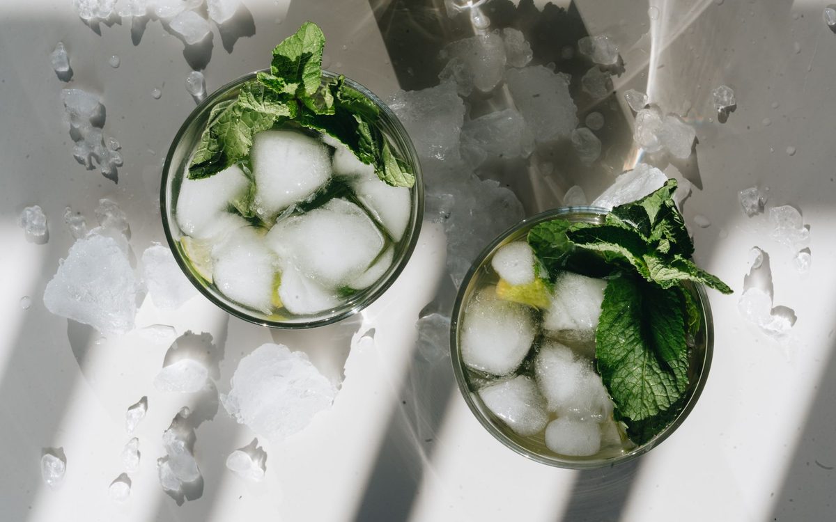 Overhead shot of mojito cocktails with ice and mint leaves, perfect for a cool refreshment.