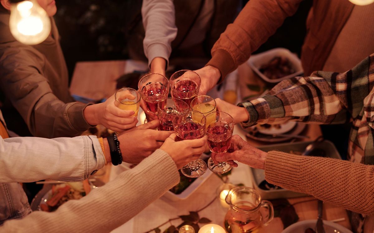 A group of people toasting with glasses of wine over a candlelit dinner table