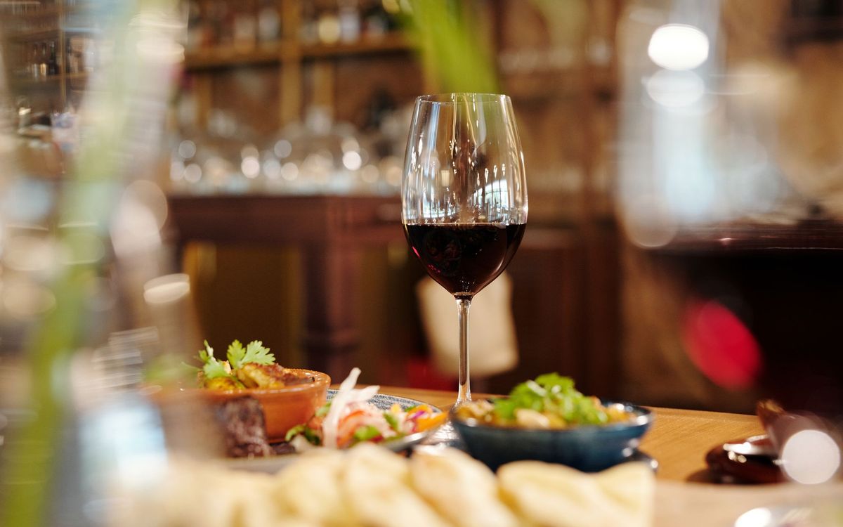 Close-up of a red wine glass amidst a variety of appetizing dishes on a restaurant table