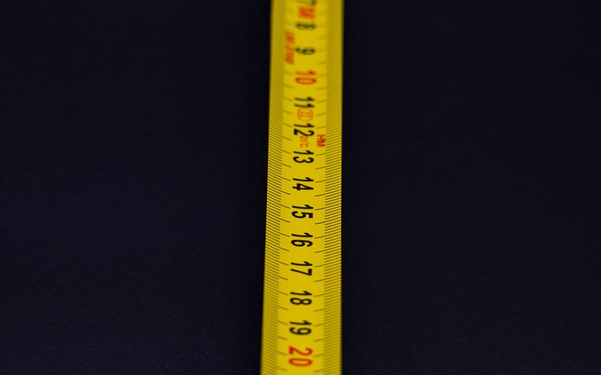 Detailed shot of a yellow measuring tape with numbers on a dark background