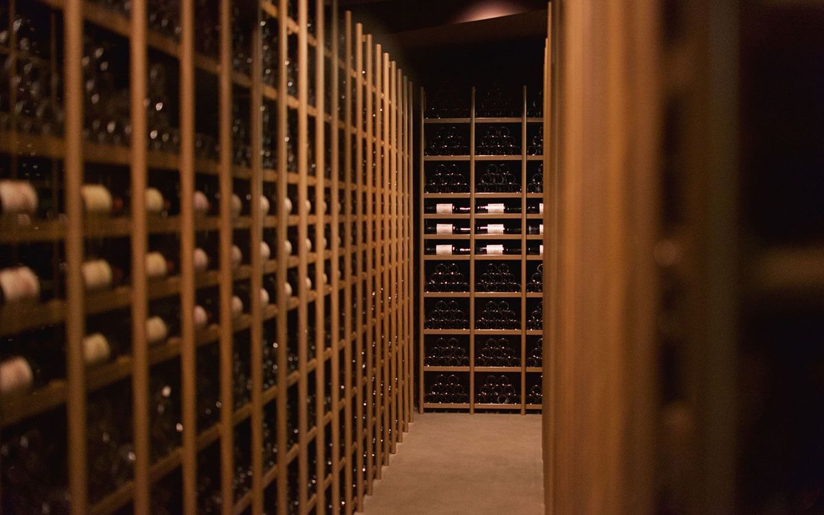 Rows of wine bottles displayed on racks in a wine cellar, the storage a wine fridge imitates at home.