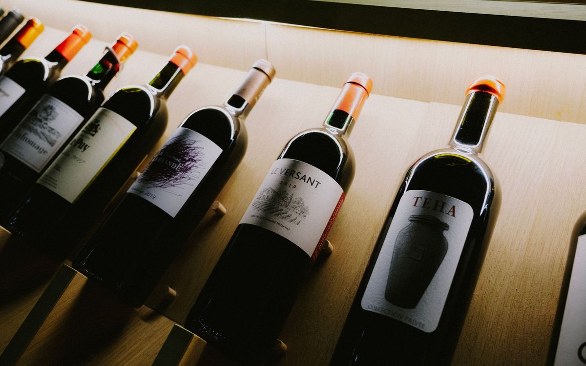 Red wine bottles on a wooden display shelf, stored on their sides for steady cork contact.