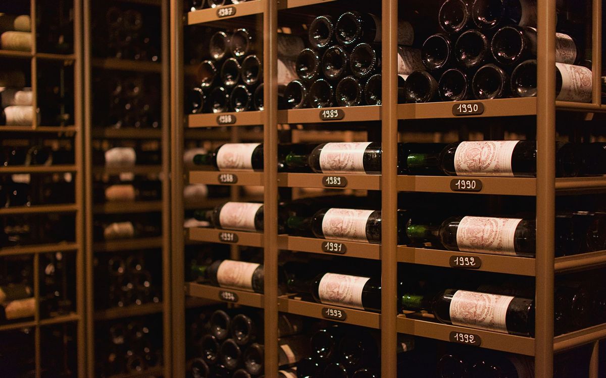 Vintage red wine bottles resting in a stone wine cellar, the traditional alternative to a wine fridge.