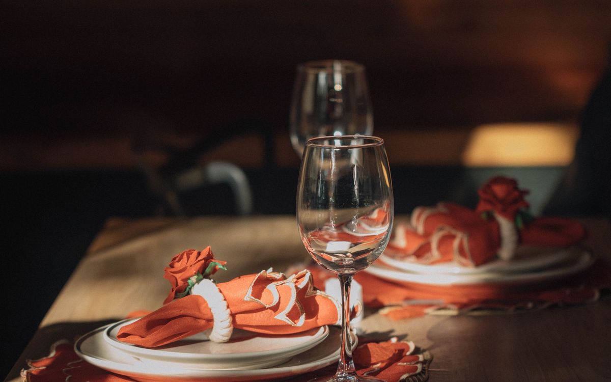 Elegant dining table with wine glasses and red rose napkin decorations