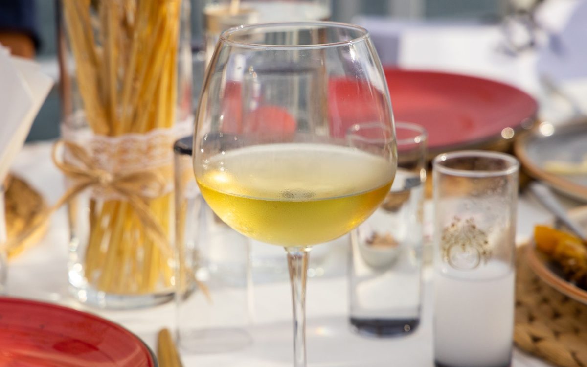 Elegant wine glass with white wine amidst table setting at an outdoor dining area