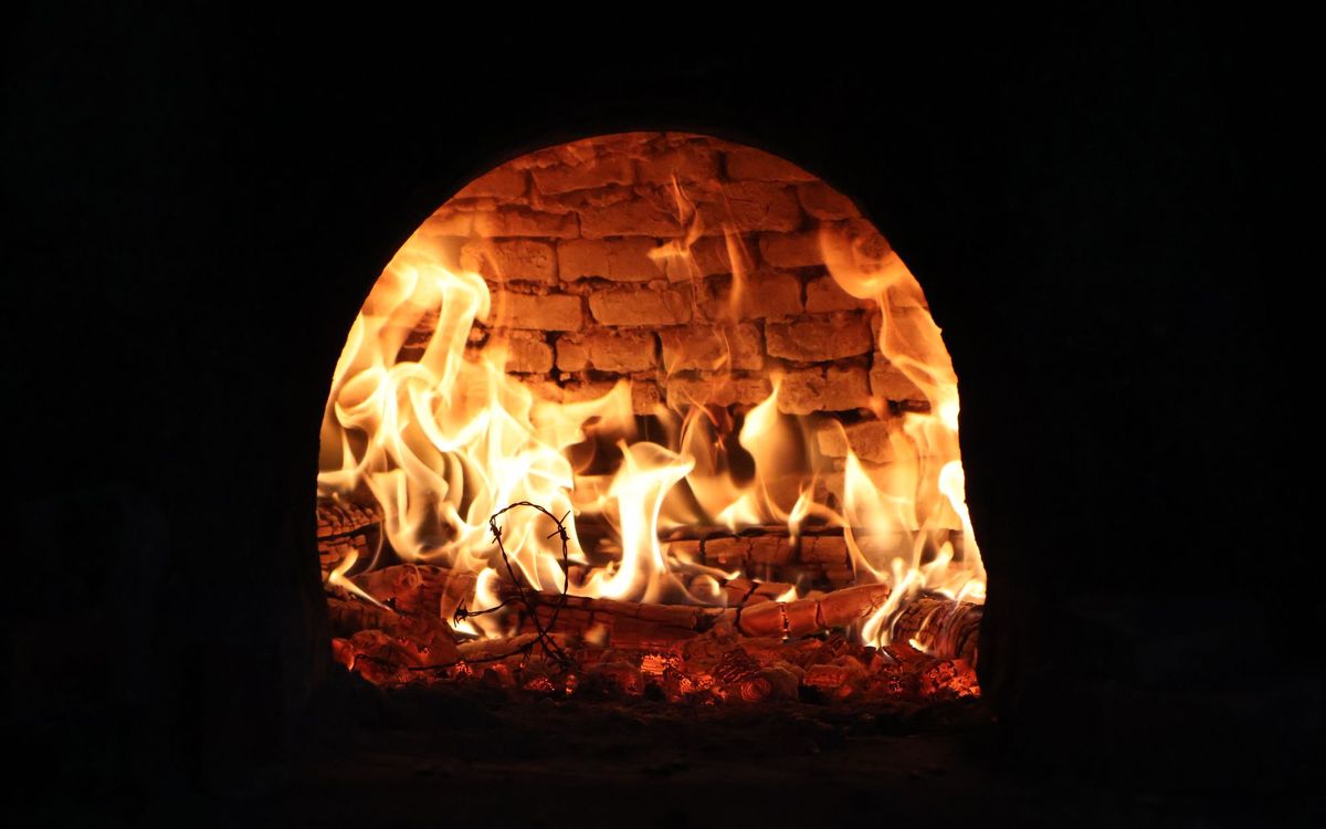 Flames and glowing coals inside a brick wood-fired oven