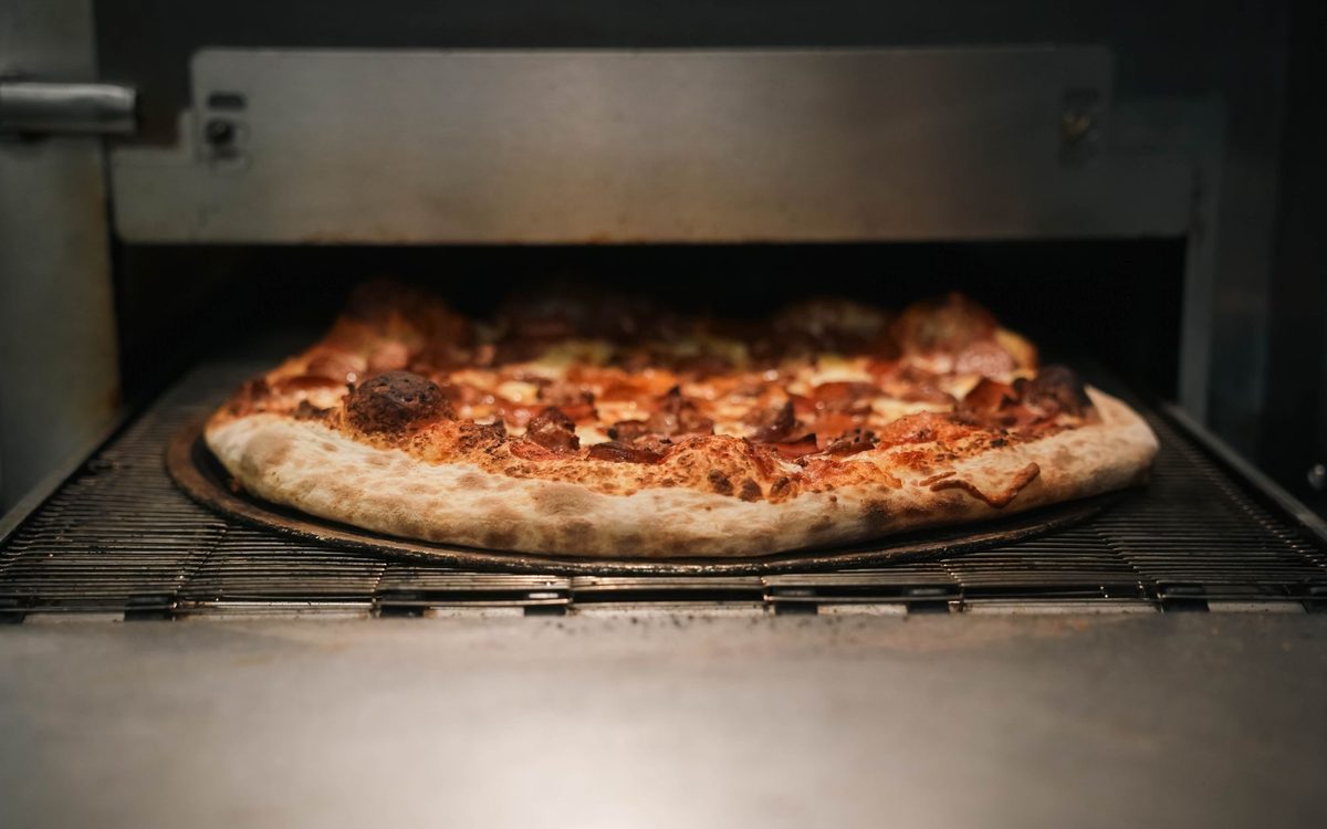 Close-up of a pepperoni pizza baking in a very hot oven