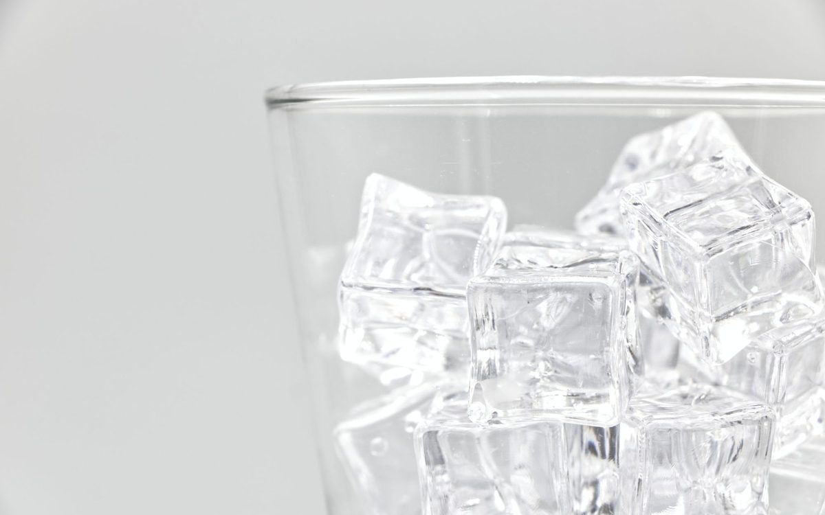 Clear ice cubes in a glass against a plain background, the quality of ice a clean countertop ice maker should deliver