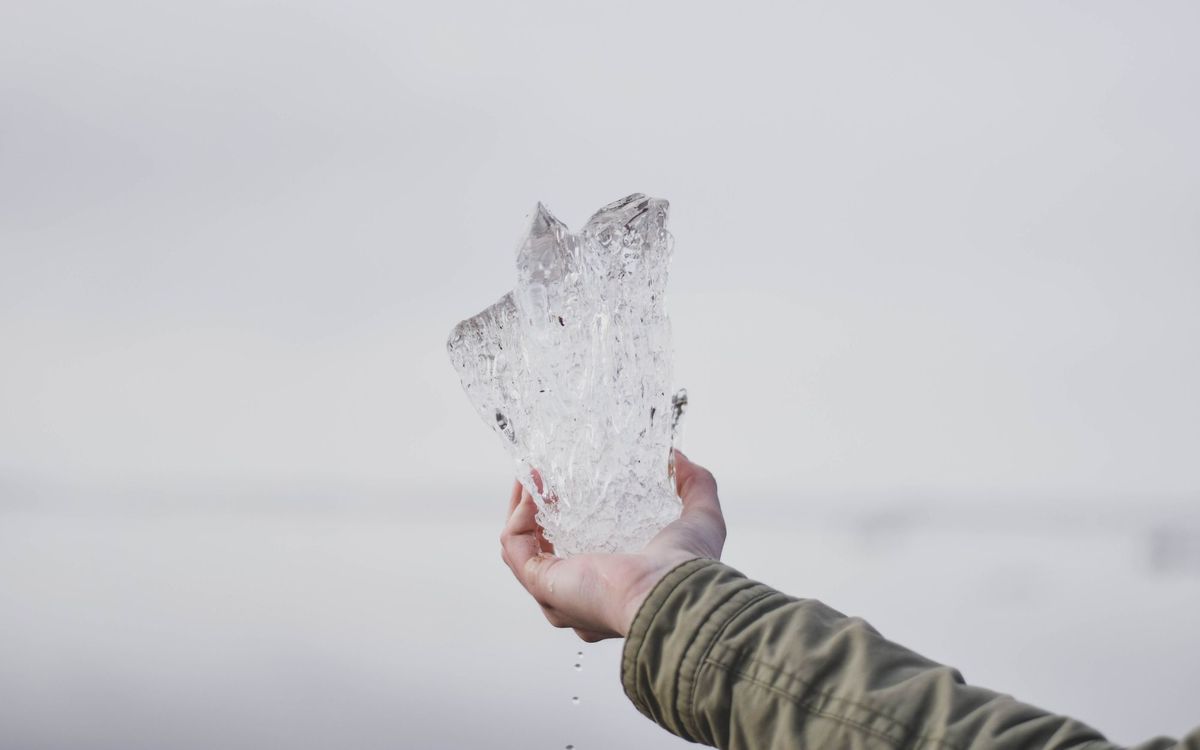 Hand holding a large chunk of clear ice that can be broken into smaller crushed pieces