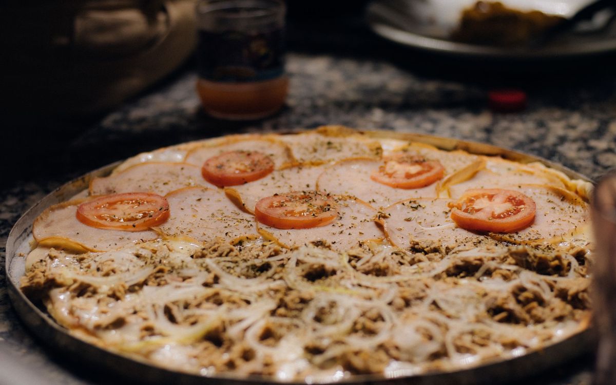 Freshly baked pizza topped with cheese, tomato slices, and onions, ready to be served.