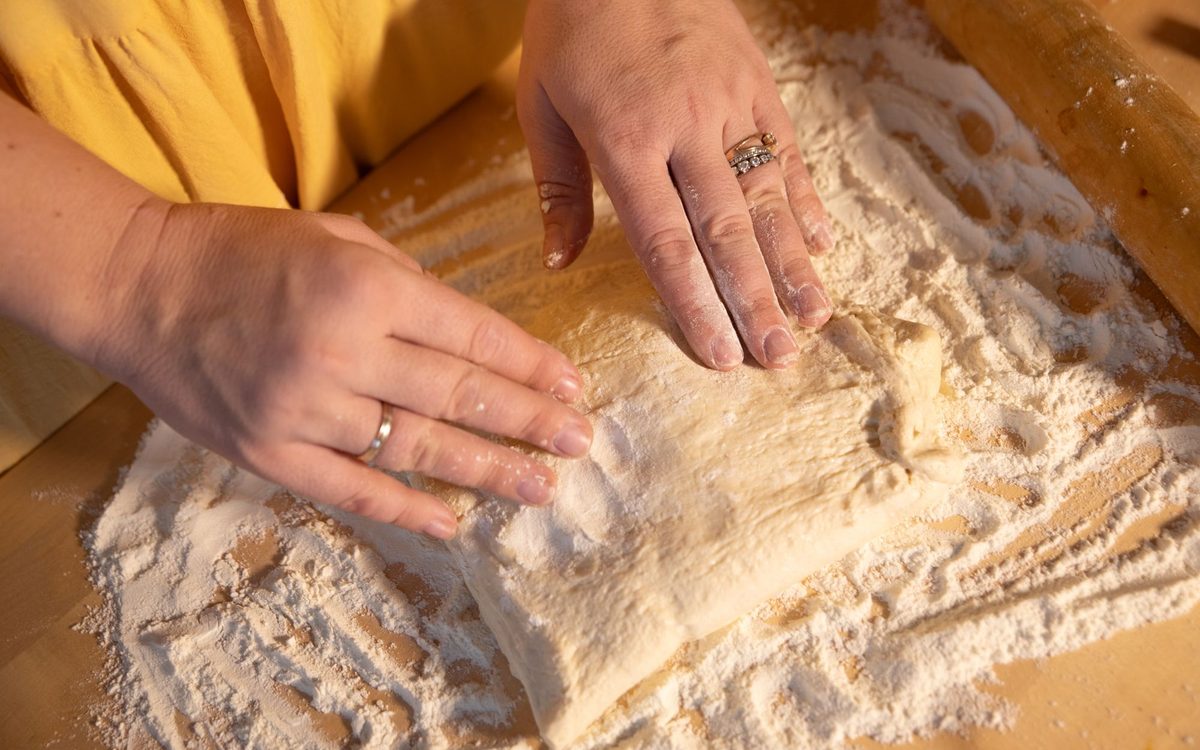 Close-up of hands kneading dough on a wooden surface with flour.