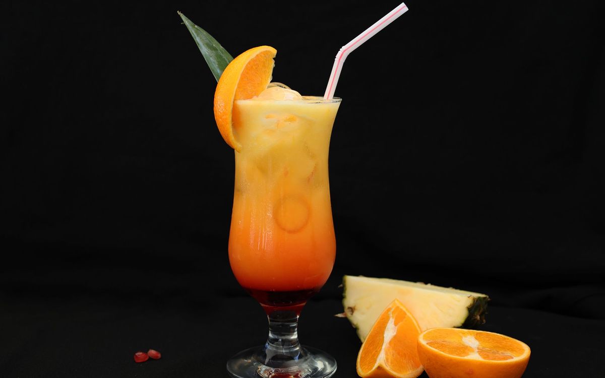 Tropical rum cocktail over ice with an orange and pineapple garnish