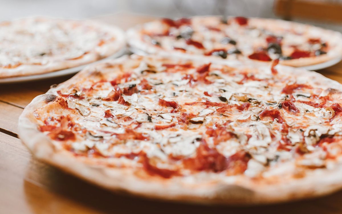 Close-up of freshly baked pizzas with mushrooms served on a wooden table