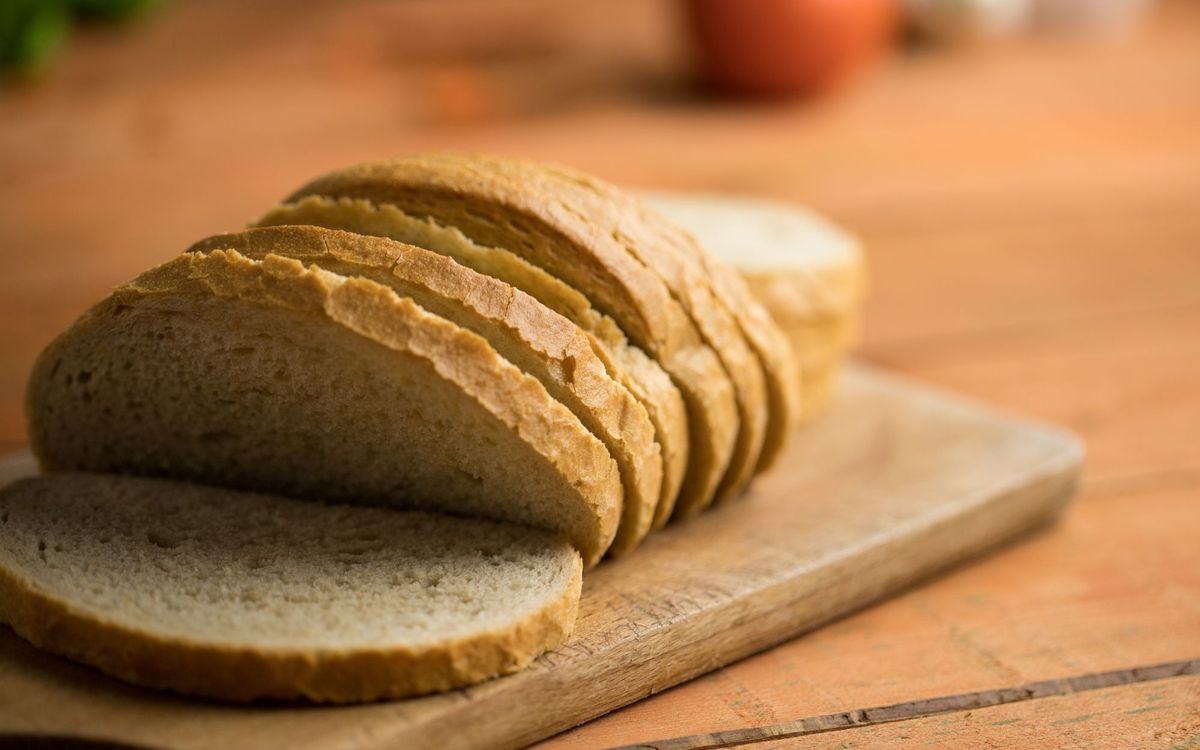 Close-up of sliced white bread on a rustic wooden board, capturing a homely and inviting look.