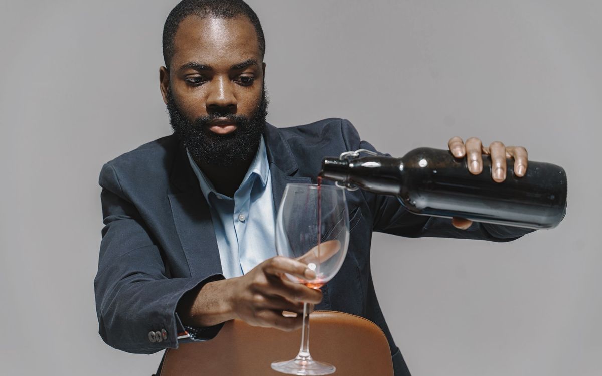 Man pouring red wine from a dark bottle into a glass