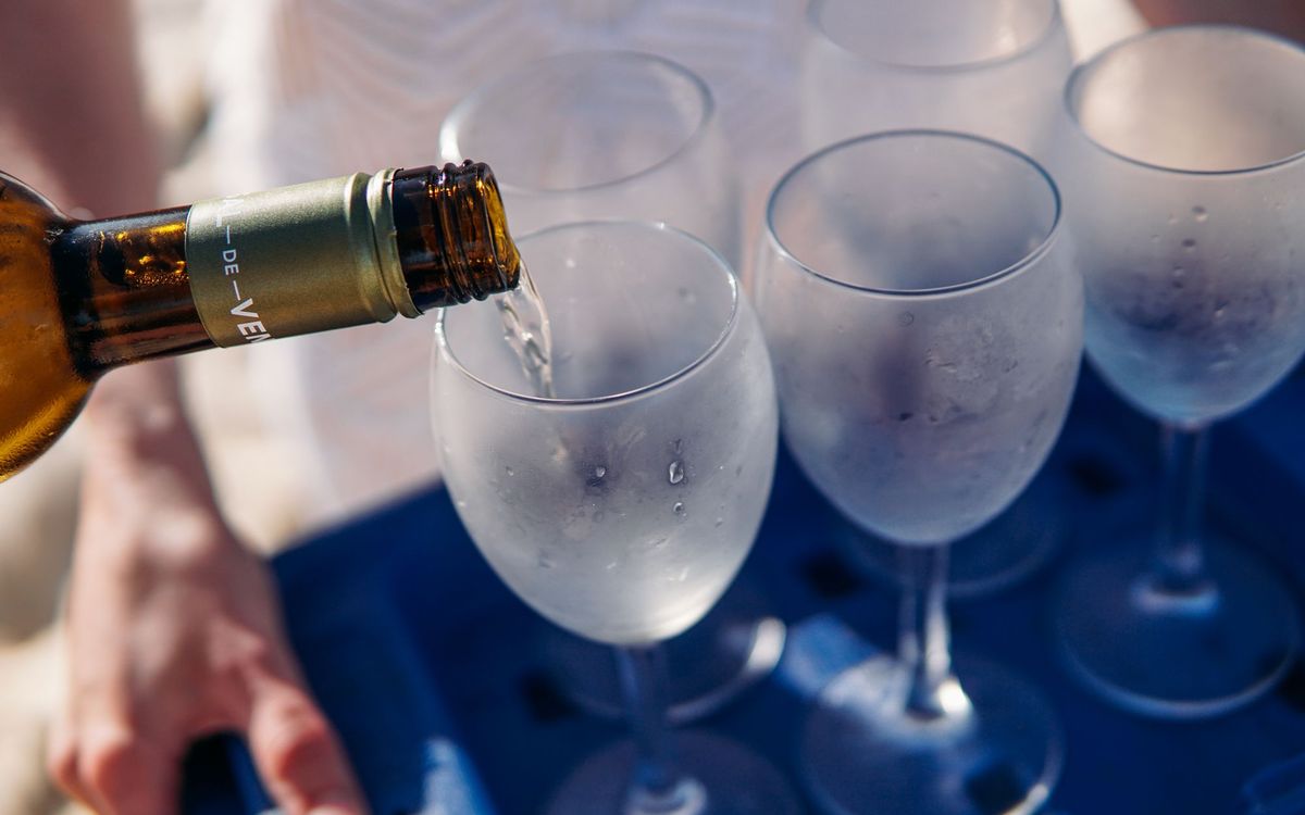 Chilled white wine being poured into frosted glasses at serving temperature.