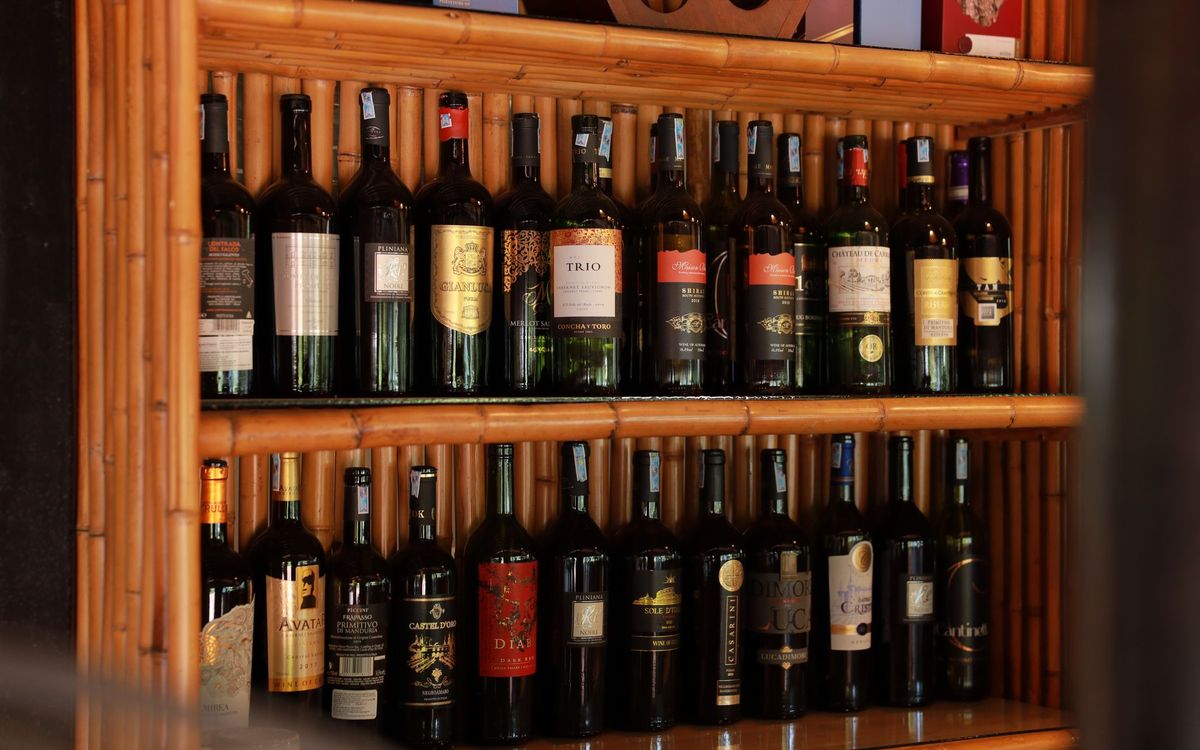 Wine bottles resting on wooden shelves in a bar setting, stored on their sides.