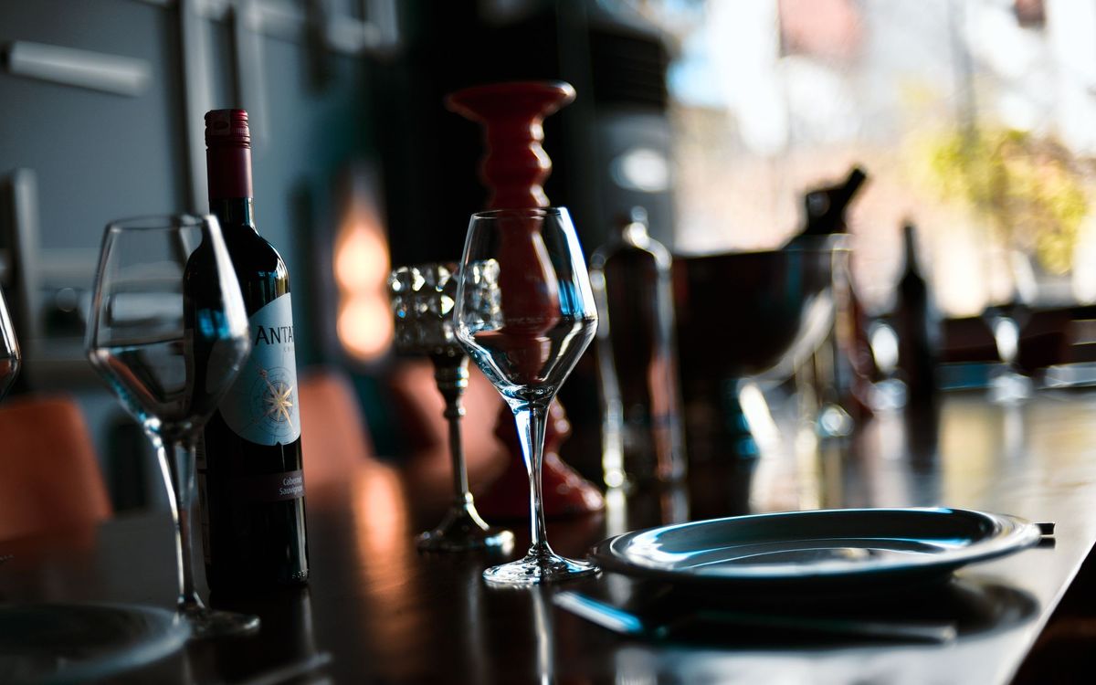 Wine glasses, a bottle and warm lighting in an indoor wine setting.